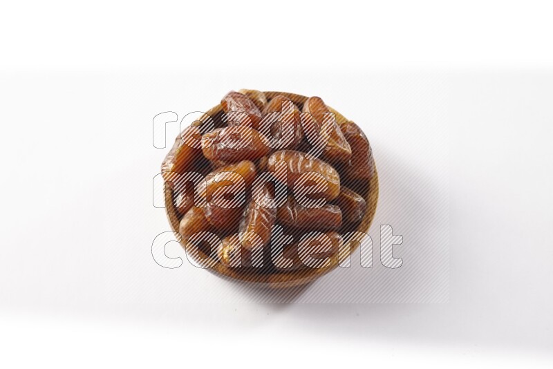 Dates in a wooden bowl on white background