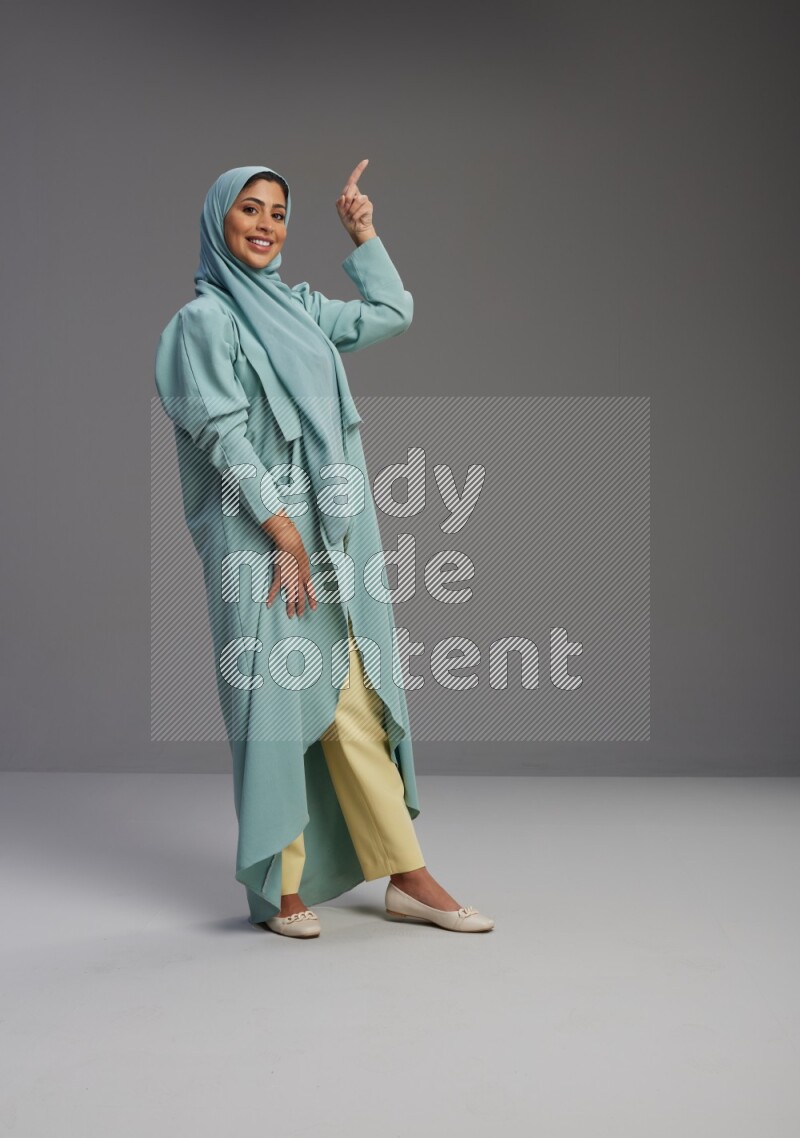 Saudi Woman wearing Abaya standing interacting with the camera on Gray background