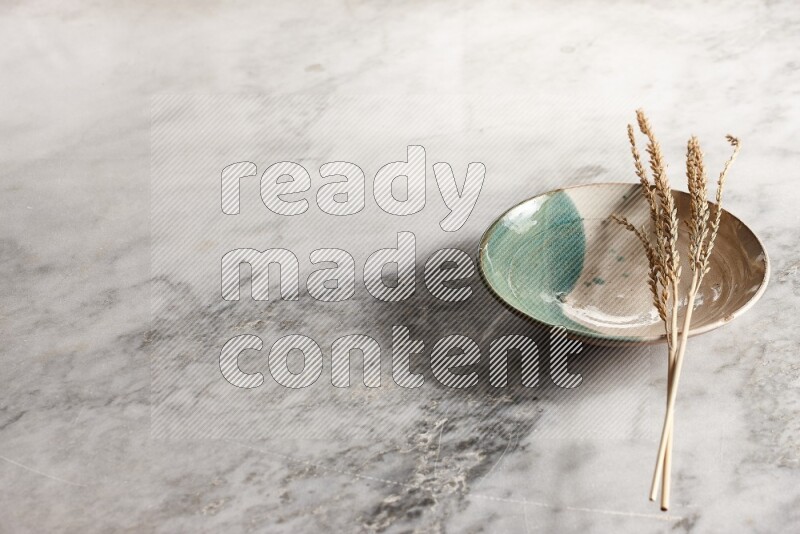 Wheat stalks on multicolored pottery plate on grey marble background
