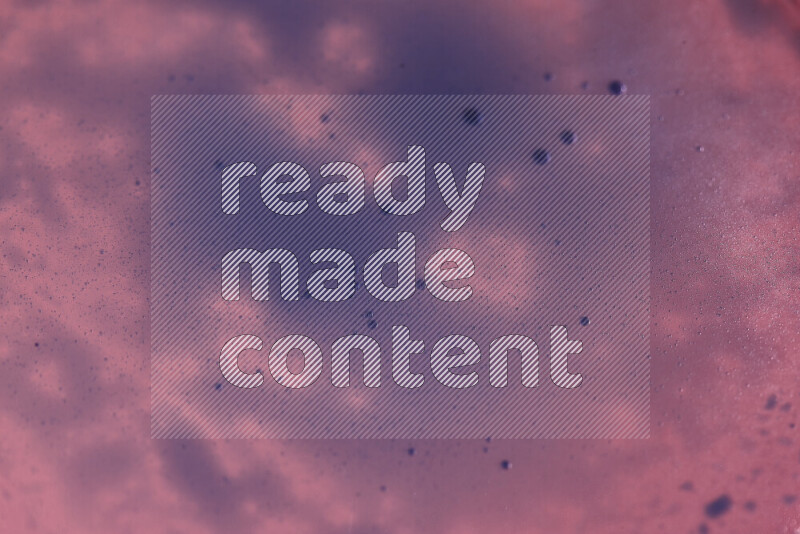 Close-ups of abstract blue watercolor drops on oil Surface on pink background