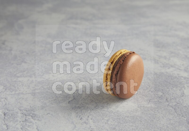 45º Shot of Yellow and Brown Chai Latte macaron on white  marble background