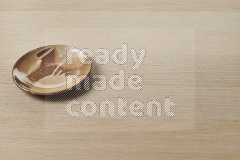 A multicolored pottery plate on light wooden background