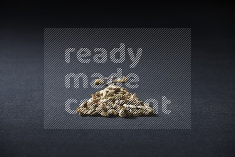 Cardamom in a triangle shape on black flooring