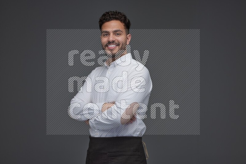 A man wearing smart casual and apron standing and making multi poses eye level on a gray background