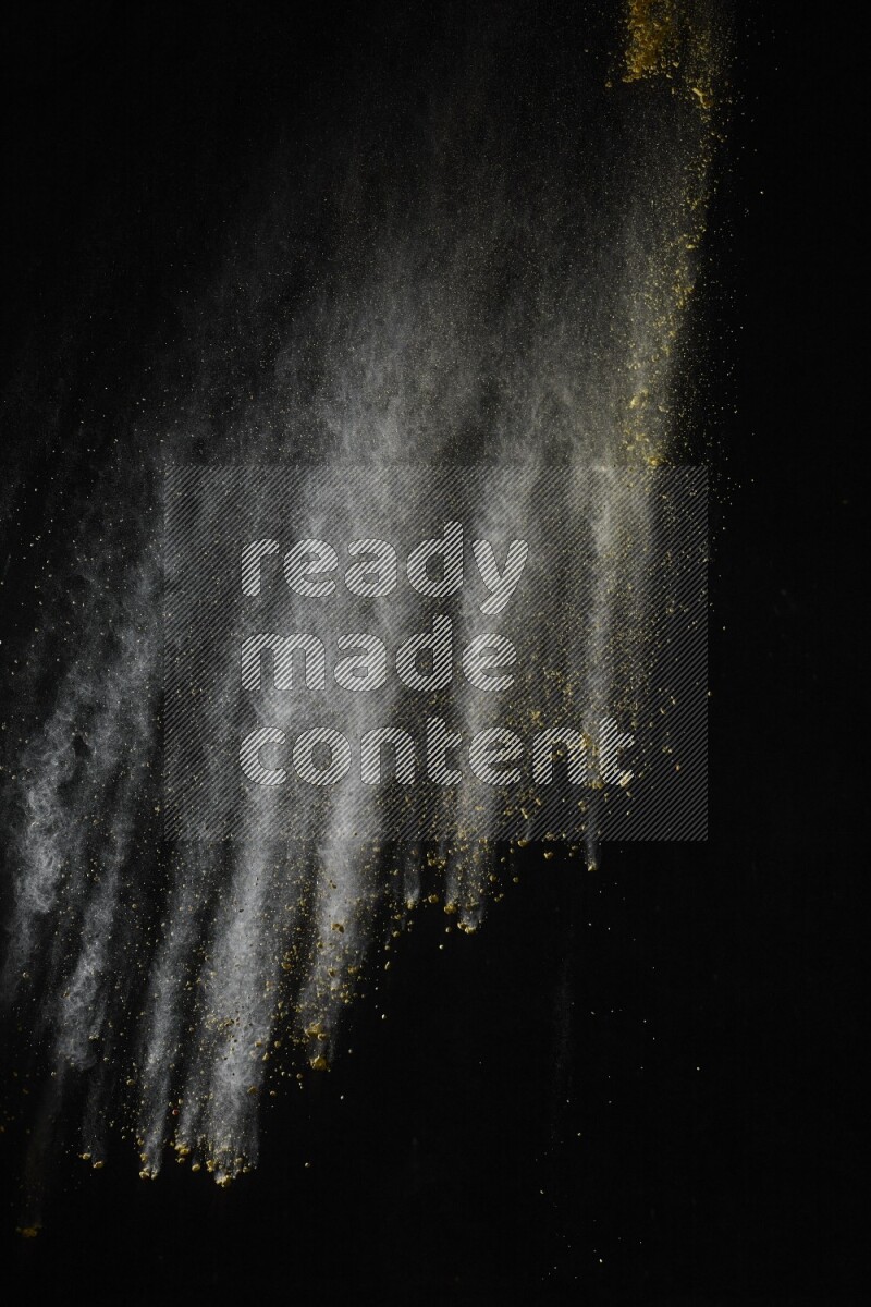A side view of yellow powder explosion on black background