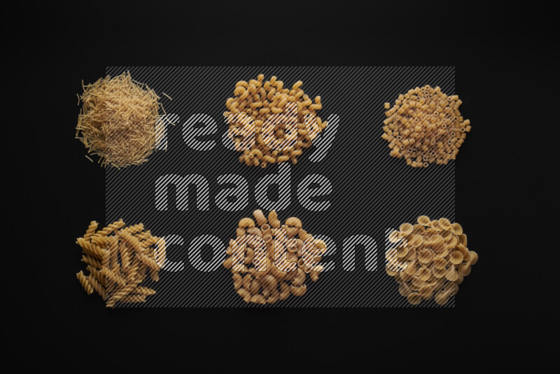 Different pasta types in bunches on black background