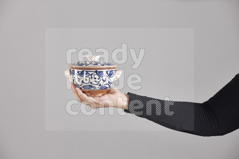 A woman in black abaya holding different pottery essentials in different positions