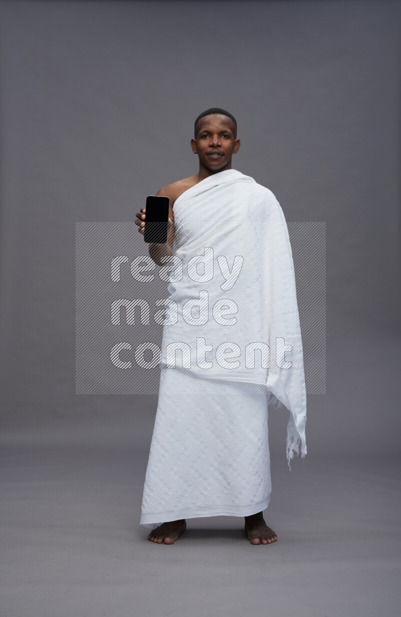 A man wearing Ehram Standing showing phone to camera on gray background