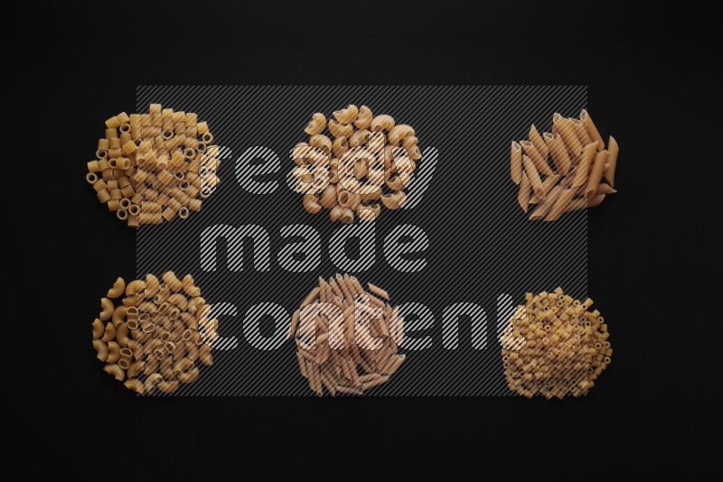 Different pasta types in bunches on black background