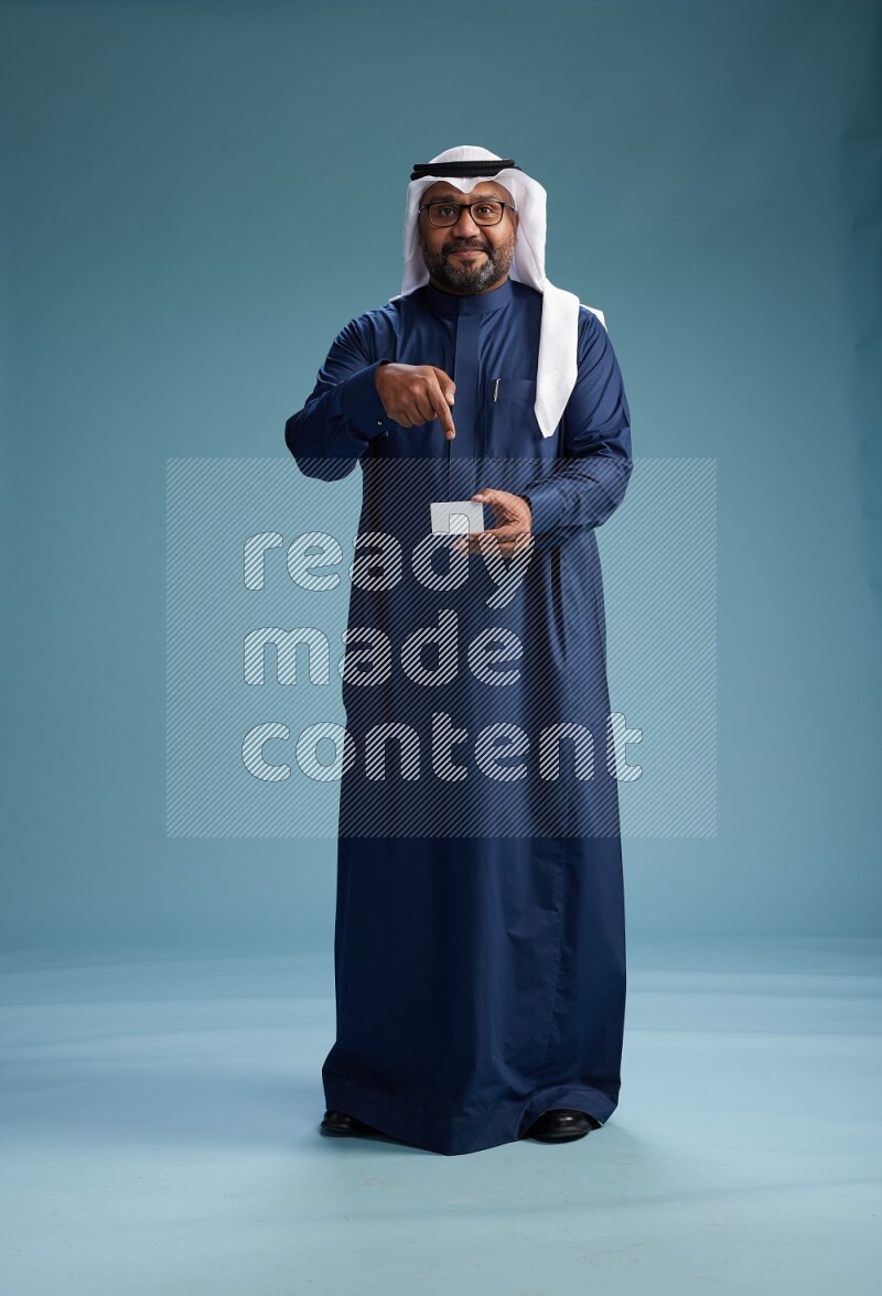 Saudi Man with shimag Standing holding ATM on blue background