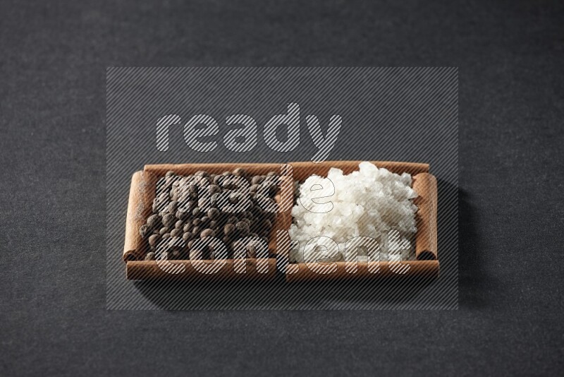 2 squares of cinnamon sticks full of white salt and allspice on black flooring
