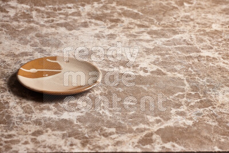 A multicolored pottery plate on beige marble background