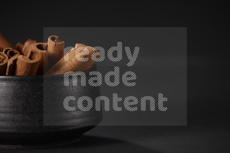 أعواد القرفة في وعاء فخاري أسود علي خلفية سوداء