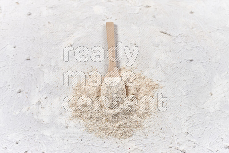 A wooden spoon full of onion powder on white background