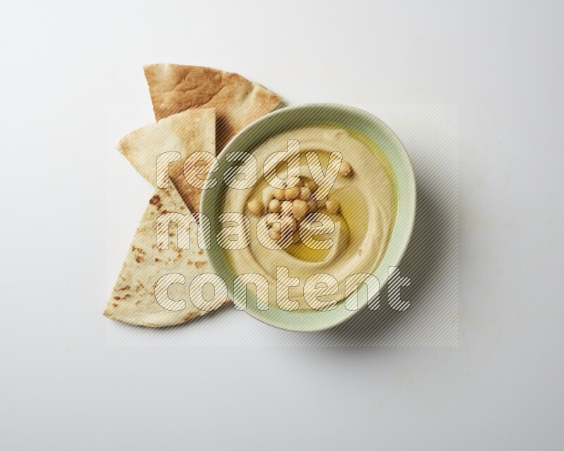 Hummus in a green plate garnished with roasted chickpeas  on a white background