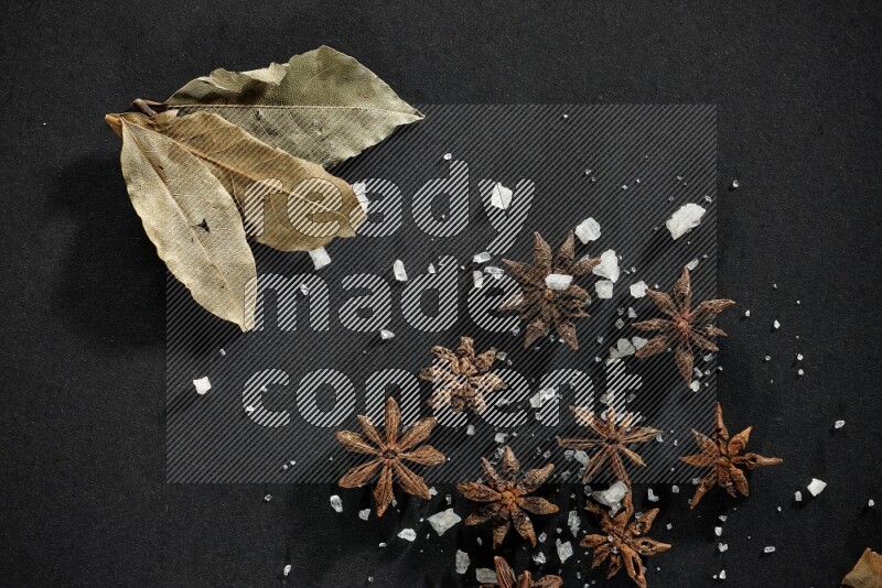 Salt, star anise and bay laurel on black flooring