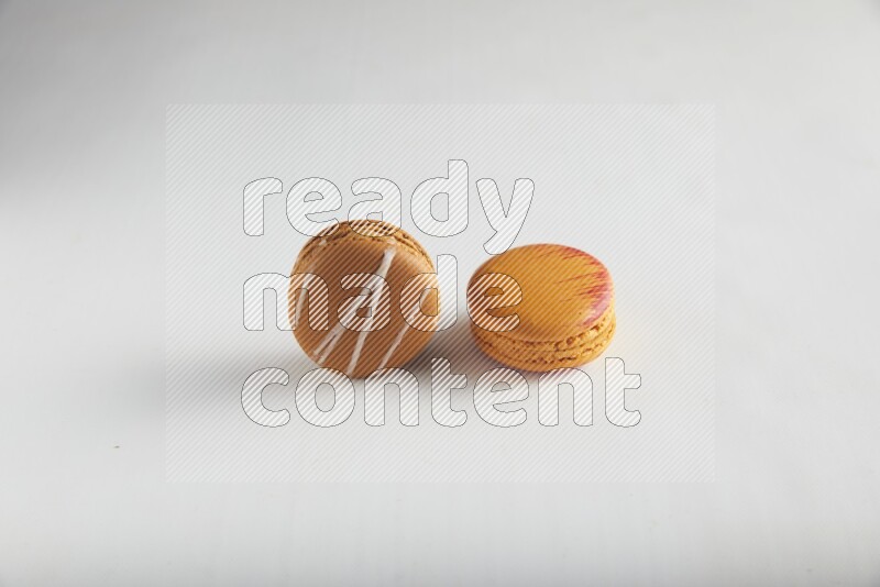 45º Shot of of two assorted Brown Irish Cream, and Orange Exotic macarons on white background