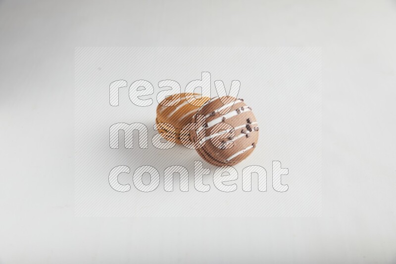 45º Shot of of two assorted Brown Irish Cream, and Brown white Chocolate Caramel macarons on white background