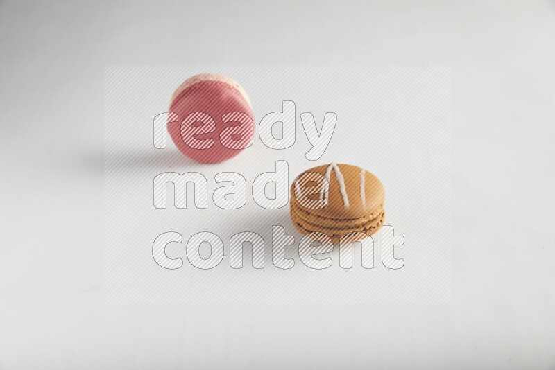 45º Shot of of two assorted Brown Irish Cream, and Pink Litchi Raspberry macarons on white background