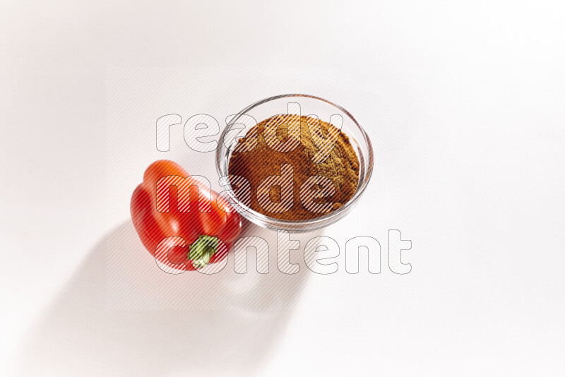 A glass bowl full of ground paprika powder on white background