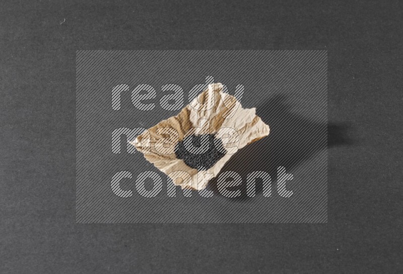 بذور حبة البركة في قطعة من الورق علي خلفية سوداء