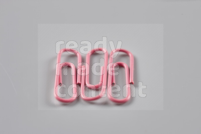 Pink paper clips isolated on a grey background