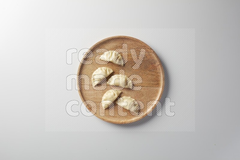Five Sambosas on a wooden round plate on a white background