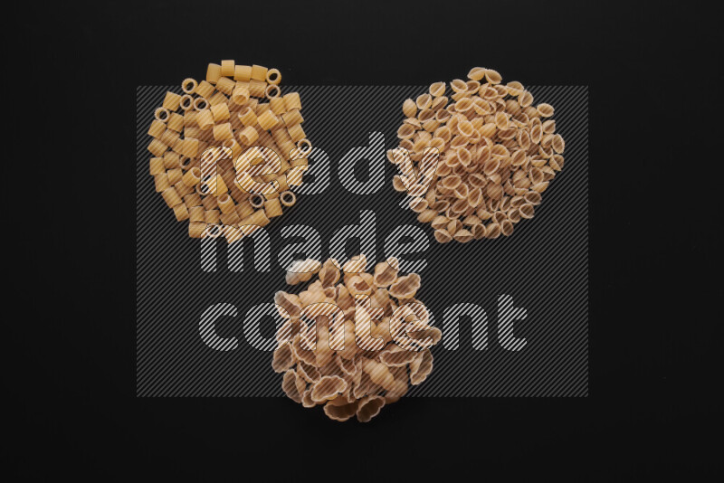 Different pasta types in bunches on black background