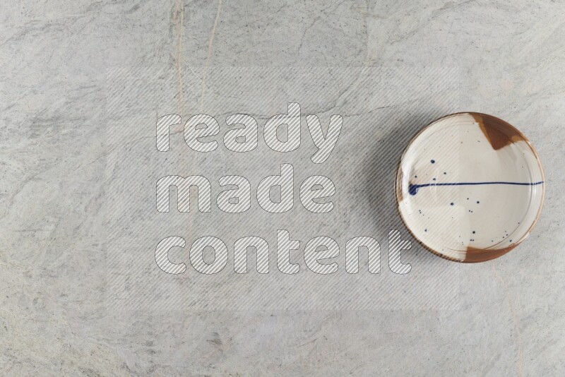 A multicolored pottery plate on grey marble background