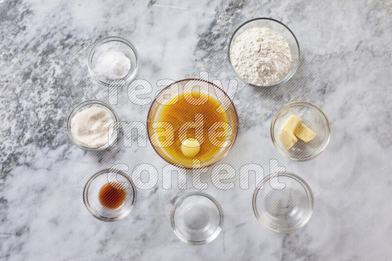 Cookies step by step with its ingredient, flour, butter, brown sugar, egg, vanilla extract, white sugar, chocolate chips and baking soda on grey marble background