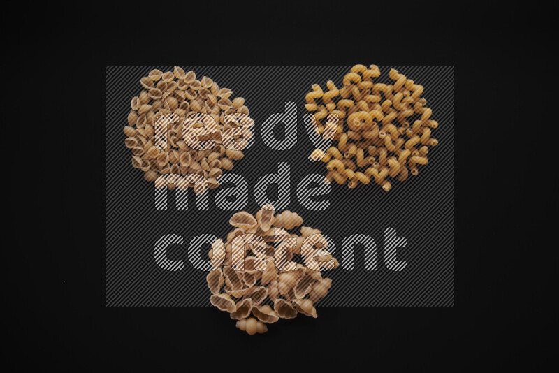 Different pasta types in bunches on black background