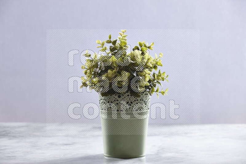 Artificial plant in green decorative pot on grey marble background