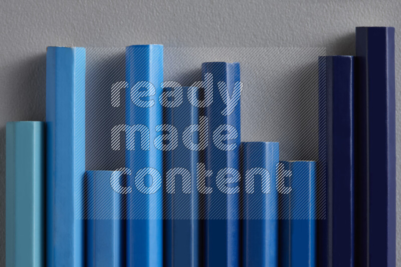 A collection of colored pencils arranged showcasing a gradient of blue hues on grey background