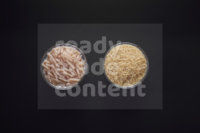 Different pasta types in glass bowls on black background