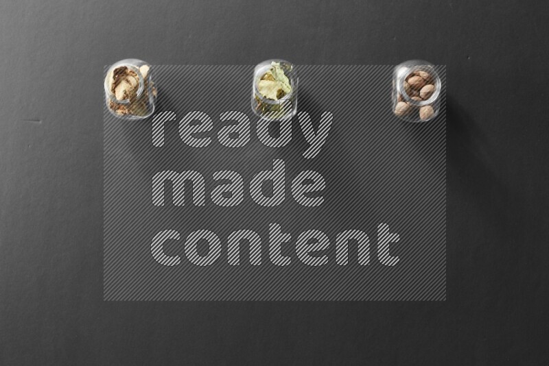 أوراق الغار وزنجبيل مجفف وجوزة الطيب في أوعية زجاجية علي خلفية سوداء