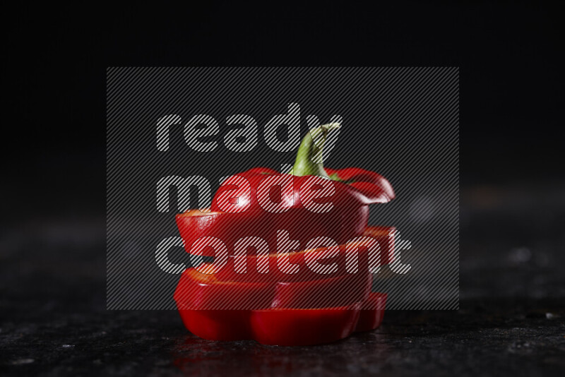 Red bell pepper slices on black background