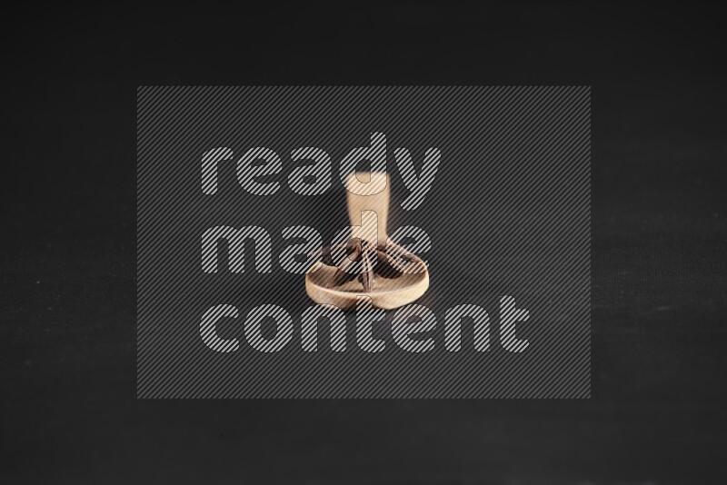 اليانسون النجمي في ملعقة خشبية فوق اليانسون النجمي الذي يغطي الإطار على أرضية سوداء