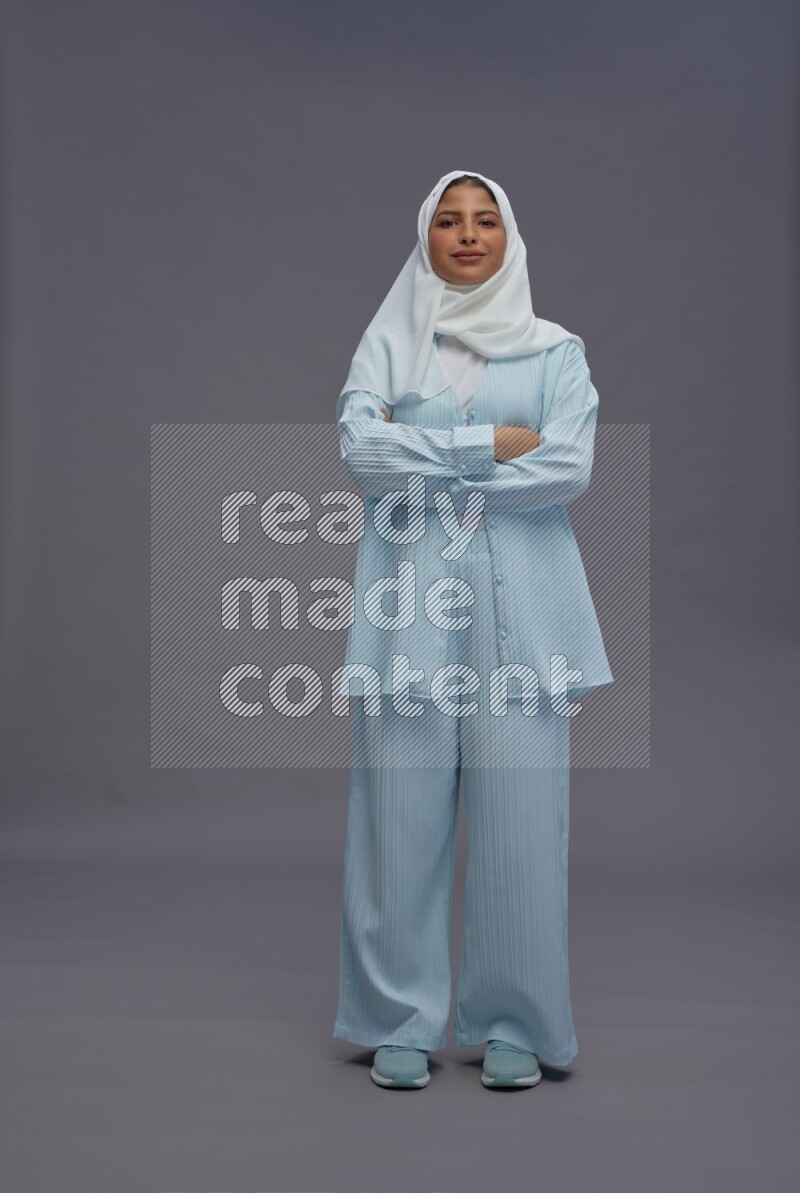 Saudi woman wearing hijab clothes standing with crossed arms on gray background