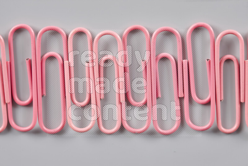 Pink paper clips isolated on a grey background