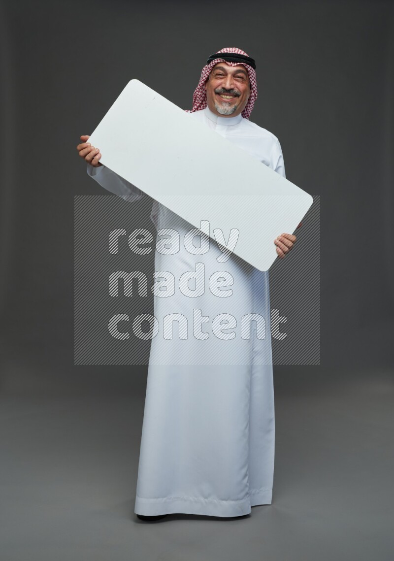 Saudi man with shomag Standing holding social media sing on gray background