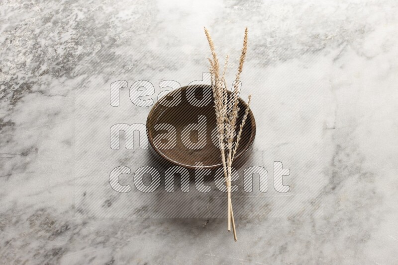 Wheat stalks on multicolored pottery oven plate on grey marble background