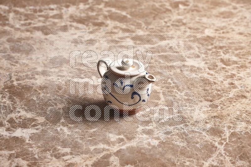 A pottery teapot on beige marble background