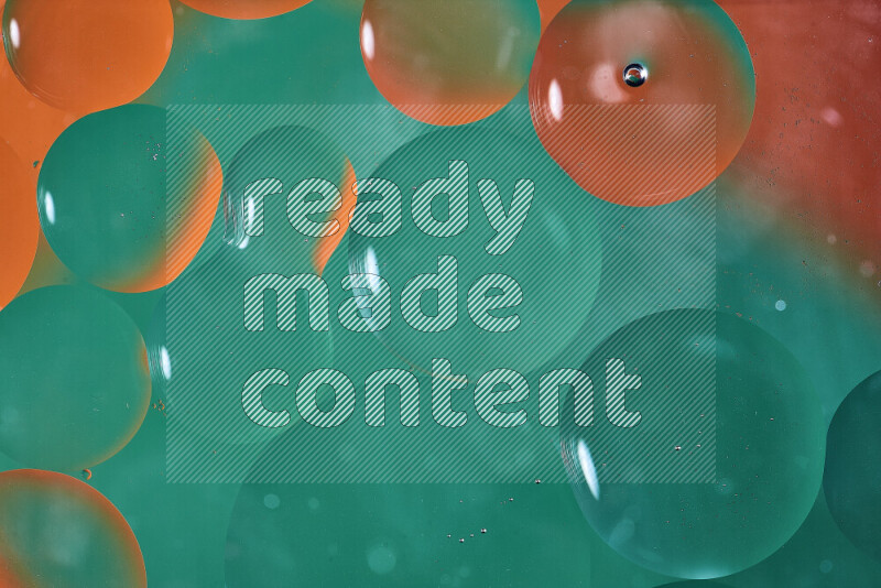 لقطات مقربة لفقاعات من الزيت على سطح الماء باللون الأخضر والبرتقالي