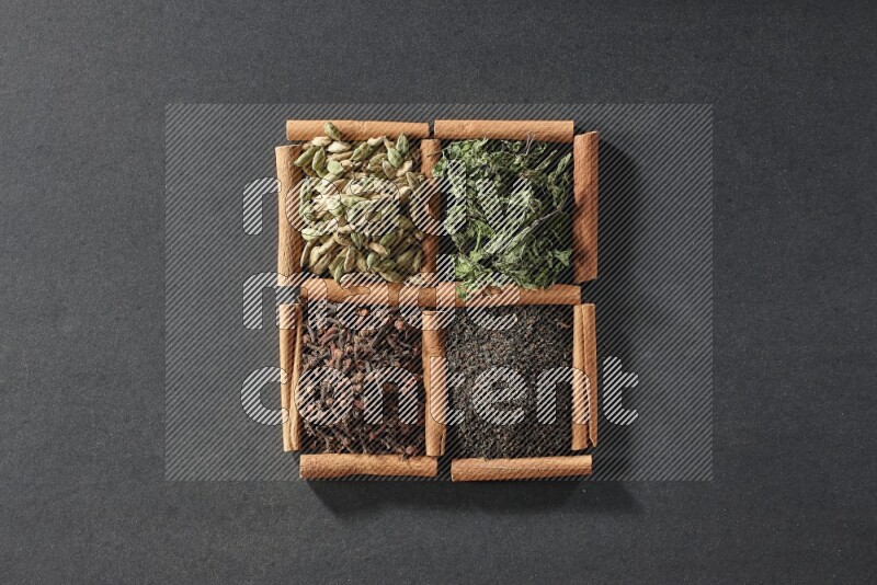4 squares of cinnamon sticks full of black tea, cloves, dried mint leaves and cardamom on black flooring