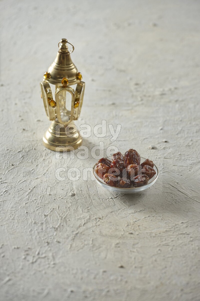 A golden lantern with different drinks, dates, nuts, prayer beads and quran on textured white background