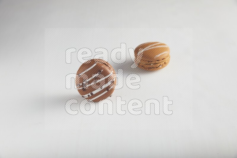 45º Shot of of two assorted Brown Irish Cream, and Brown white Chocolate Caramel macarons on white background
