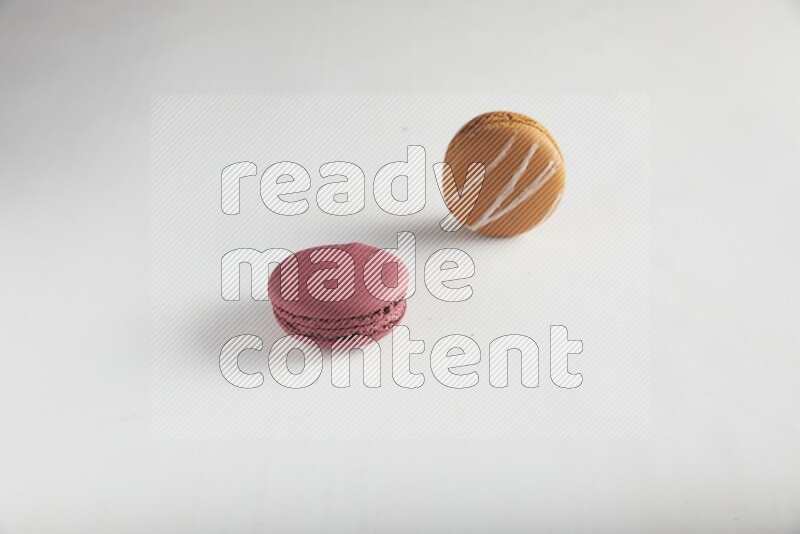 45º Shot of of two assorted Brown Irish Cream, and Red Cherry macarons on white background