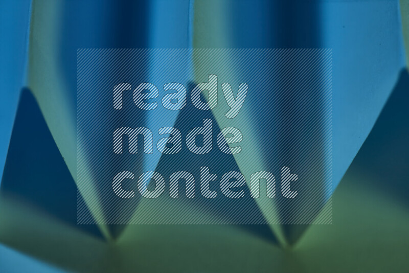 صورة مجردة مقربة تظهر طيات ورقية هندسية حادة بتدرجات اللون الأخضر والأزرق