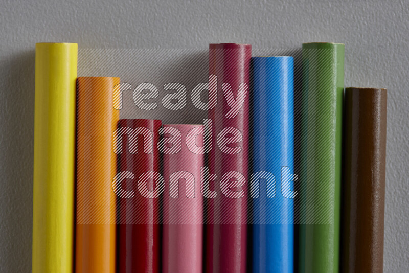 A collection of colored pencils arranged showcasing a gradient of different hues on grey background