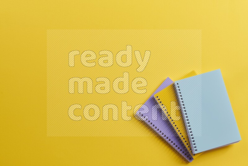 Multicolored notebooks on yellow background